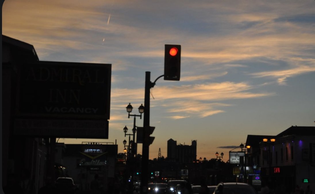 A red traffic light against a streaked sunset sky