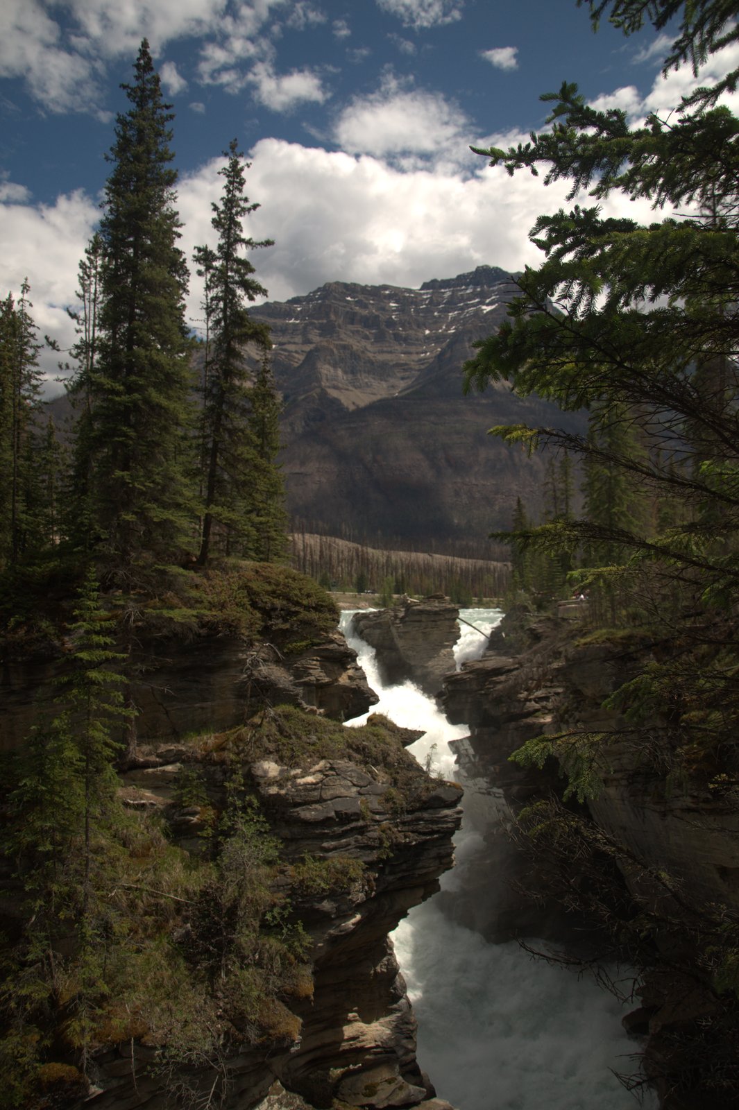 A river cutting through a rock gorge below a mountain face