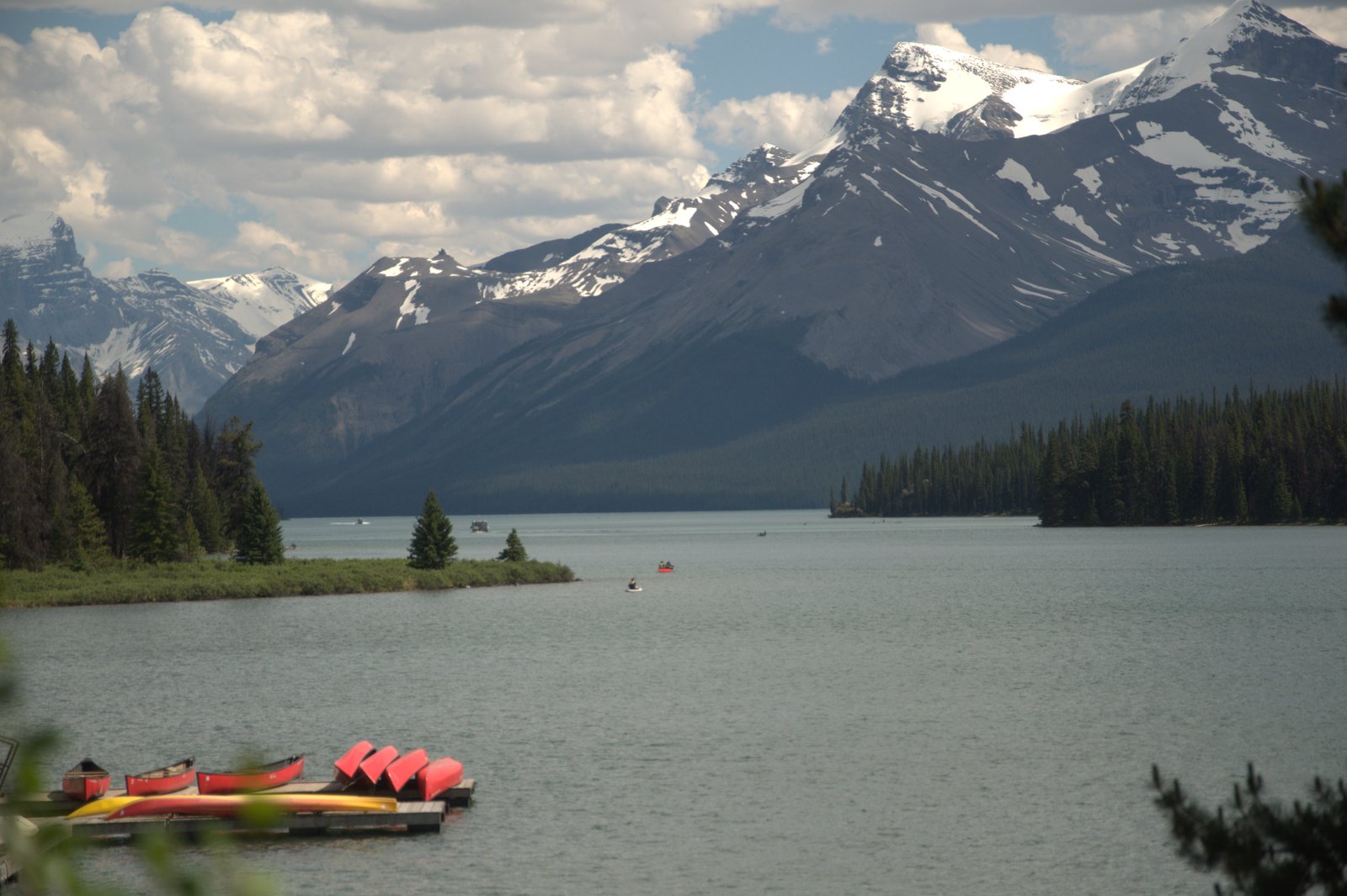 Red canoes docked on Maligne Lake with snow-capped peaks behind