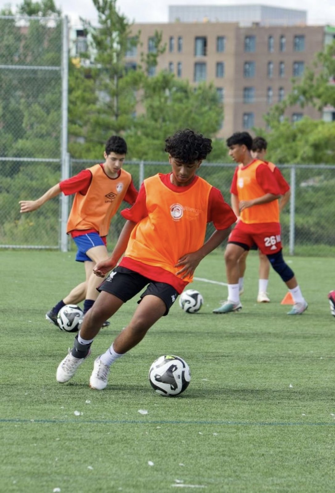 Shaurya on the ball at training, cutting past a defender in an orange bib