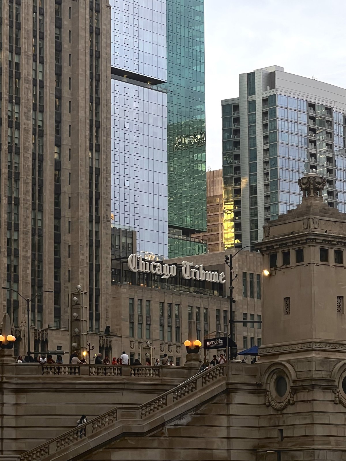 The Chicago Tribune sign among towers, seen from the Michigan Avenue bridge stairs